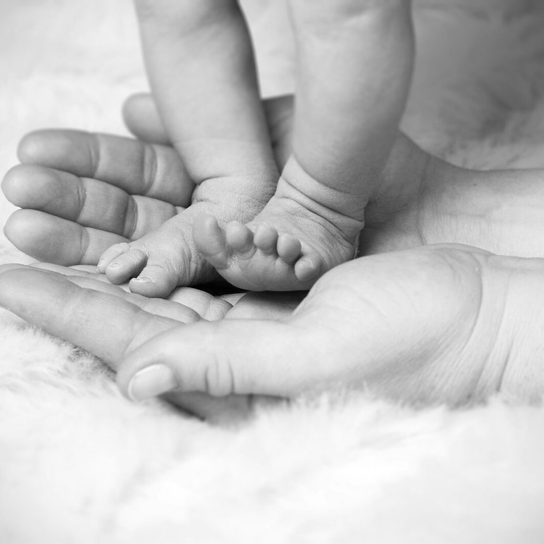 grayscale photo of baby's foot on human palm